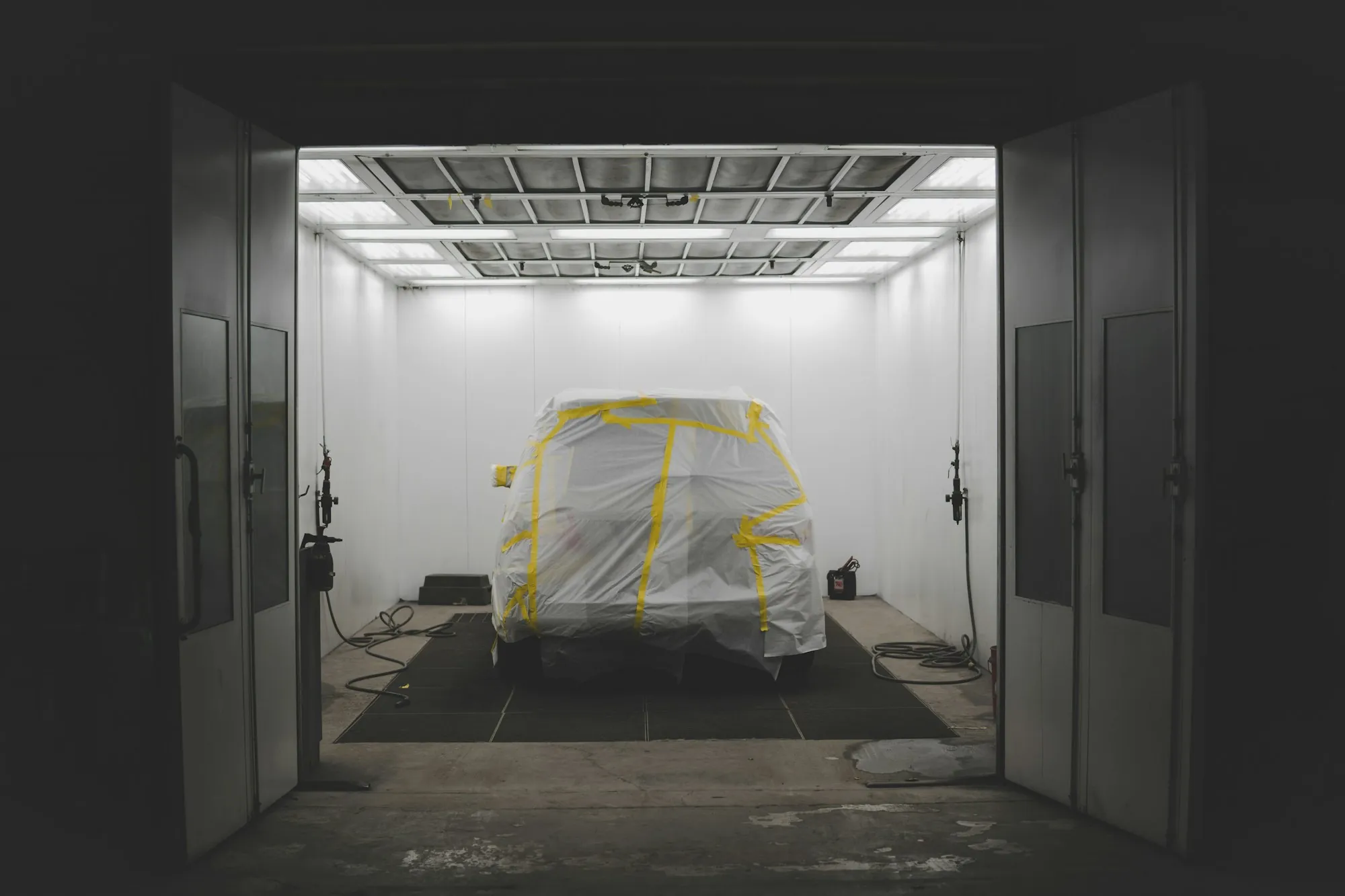 Car covered in protective sheeting inside a paint booth