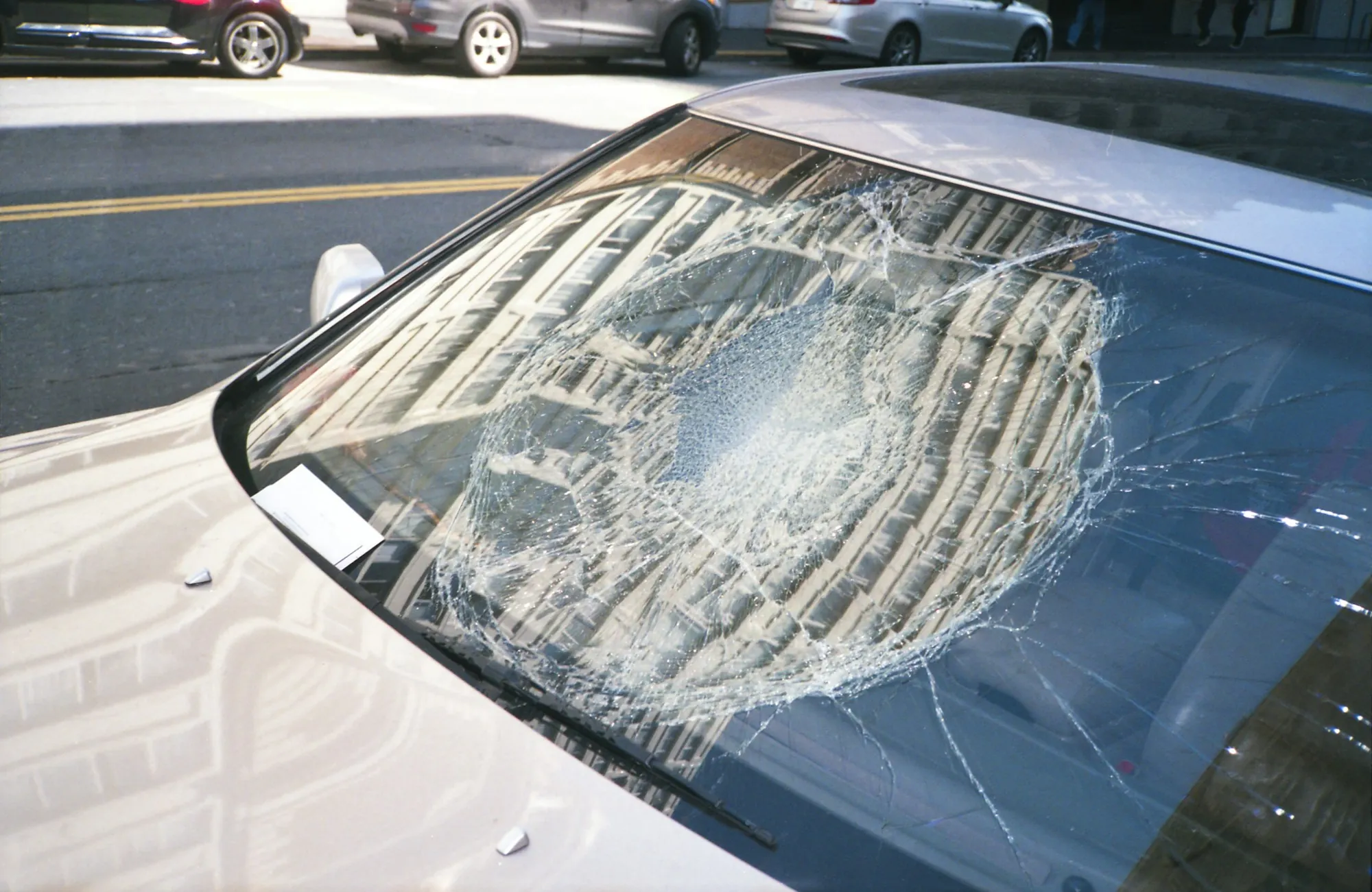 Cracked windshield being removed from a car inside a body shop