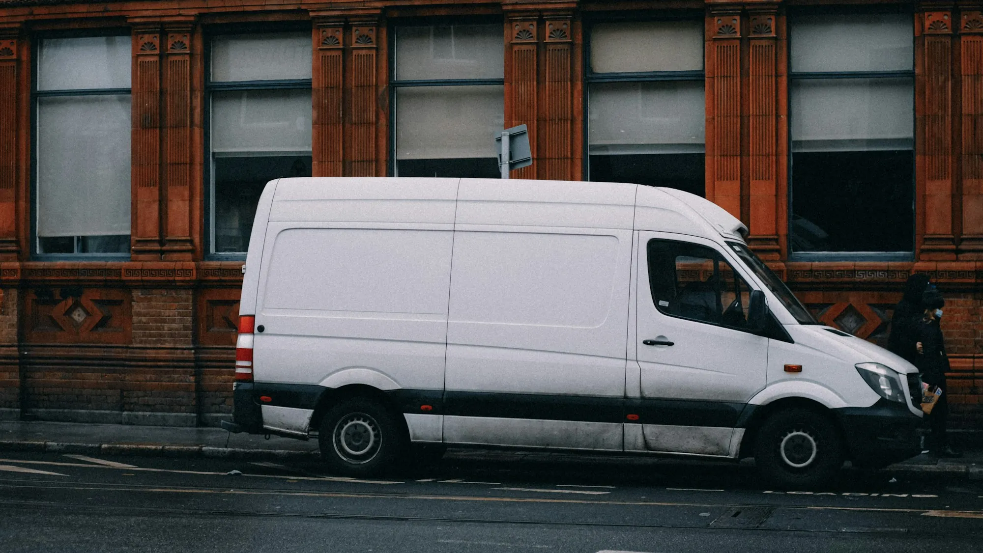 Row of white work vans parked outside a collision repair shop