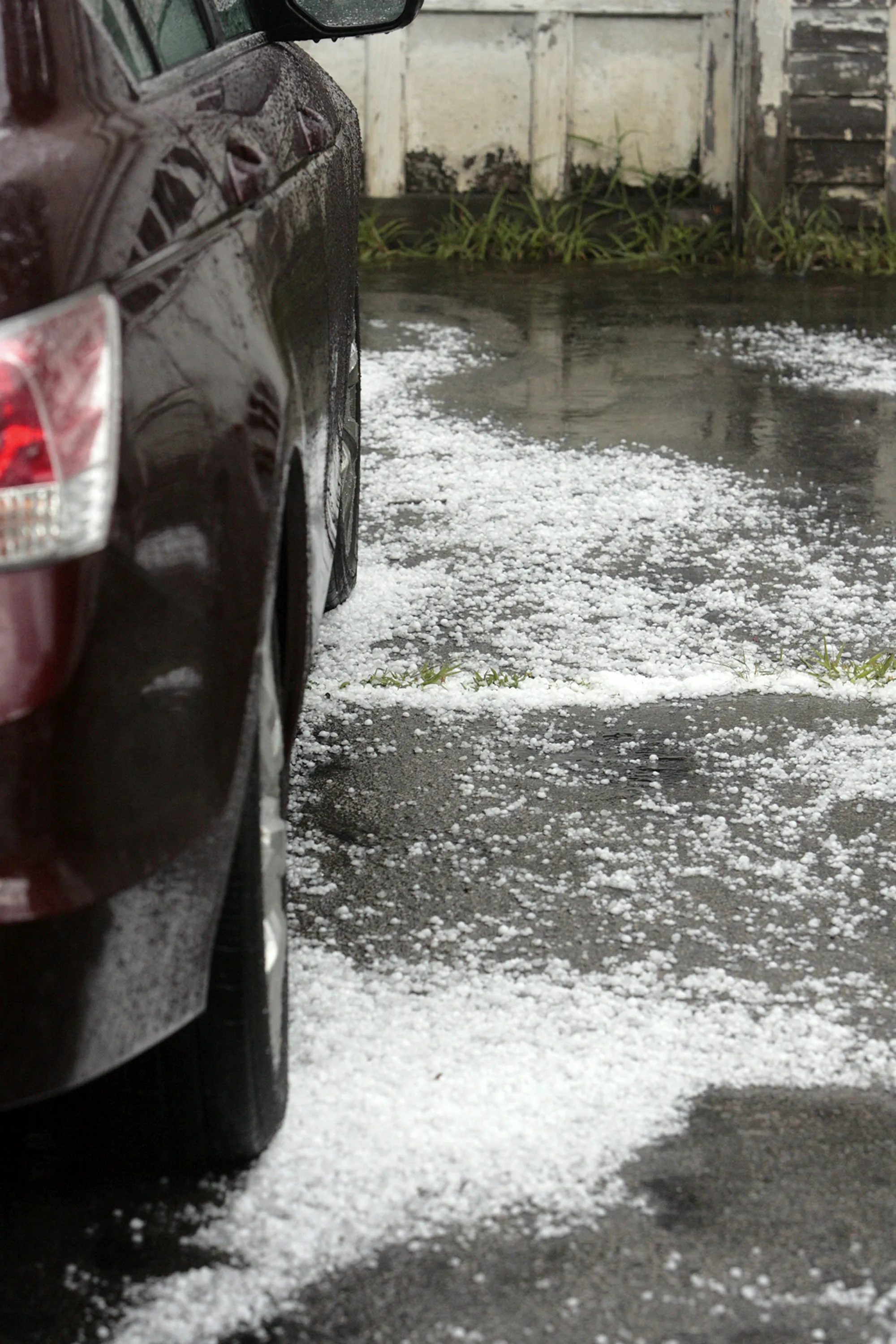 Silver sedan roof covered in small round hail dents under bright shop lights
