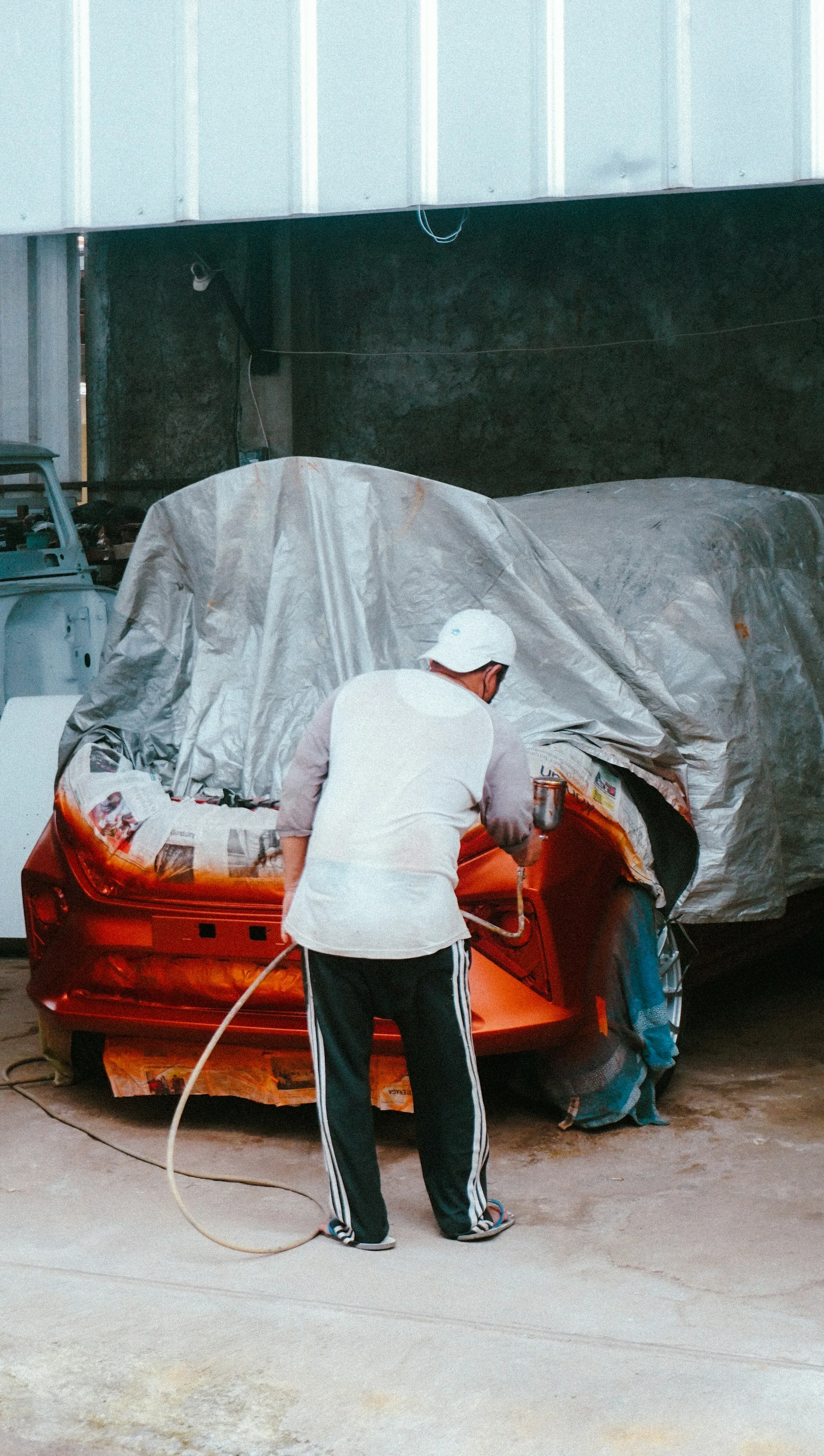 Technician masking a car body before painting