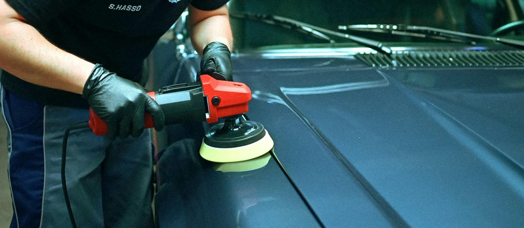 Technician using a long metal rod behind a car door to remove a small dent
