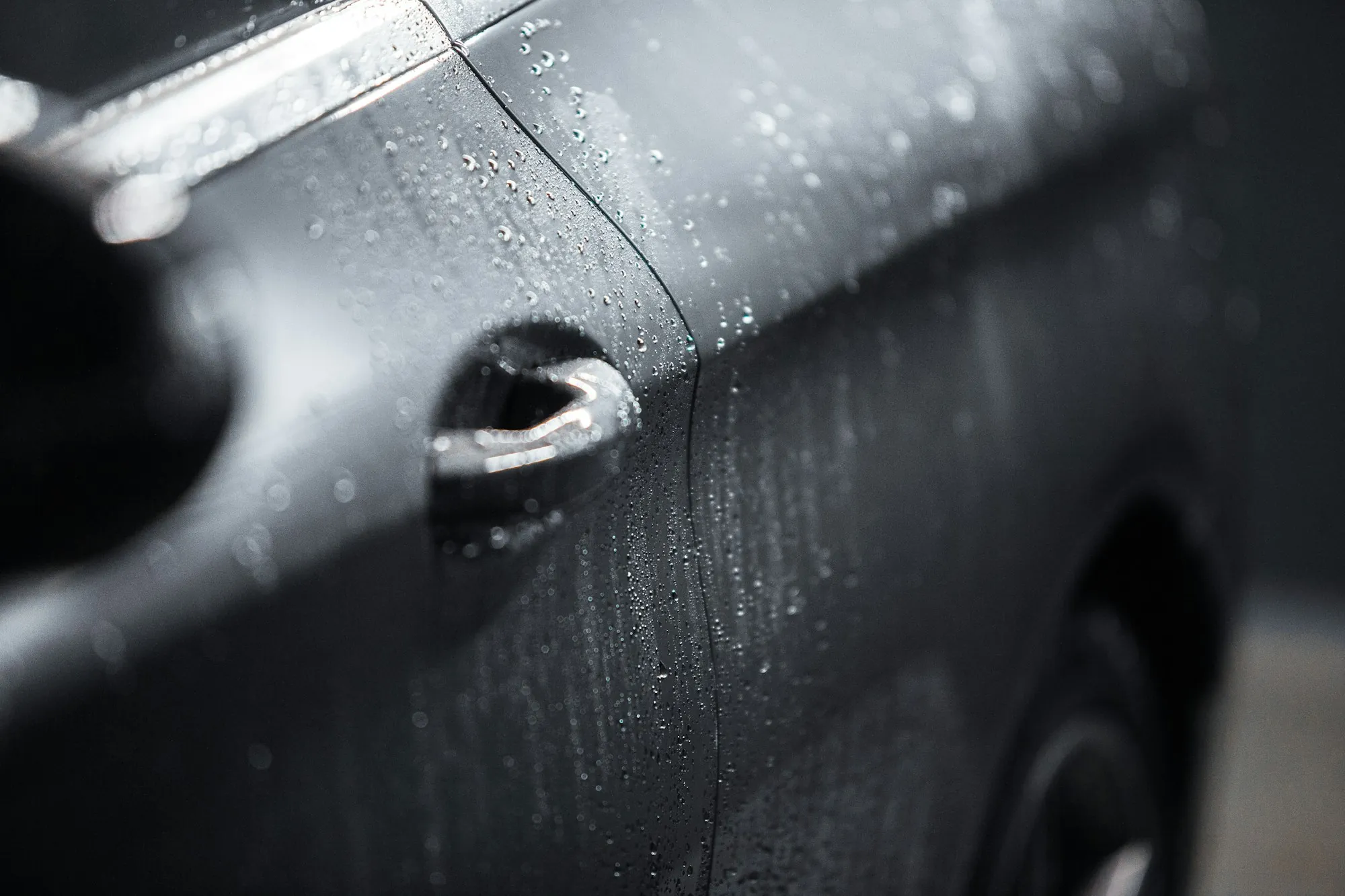 Close-up of a long scratch along the side of a dark gray car door
