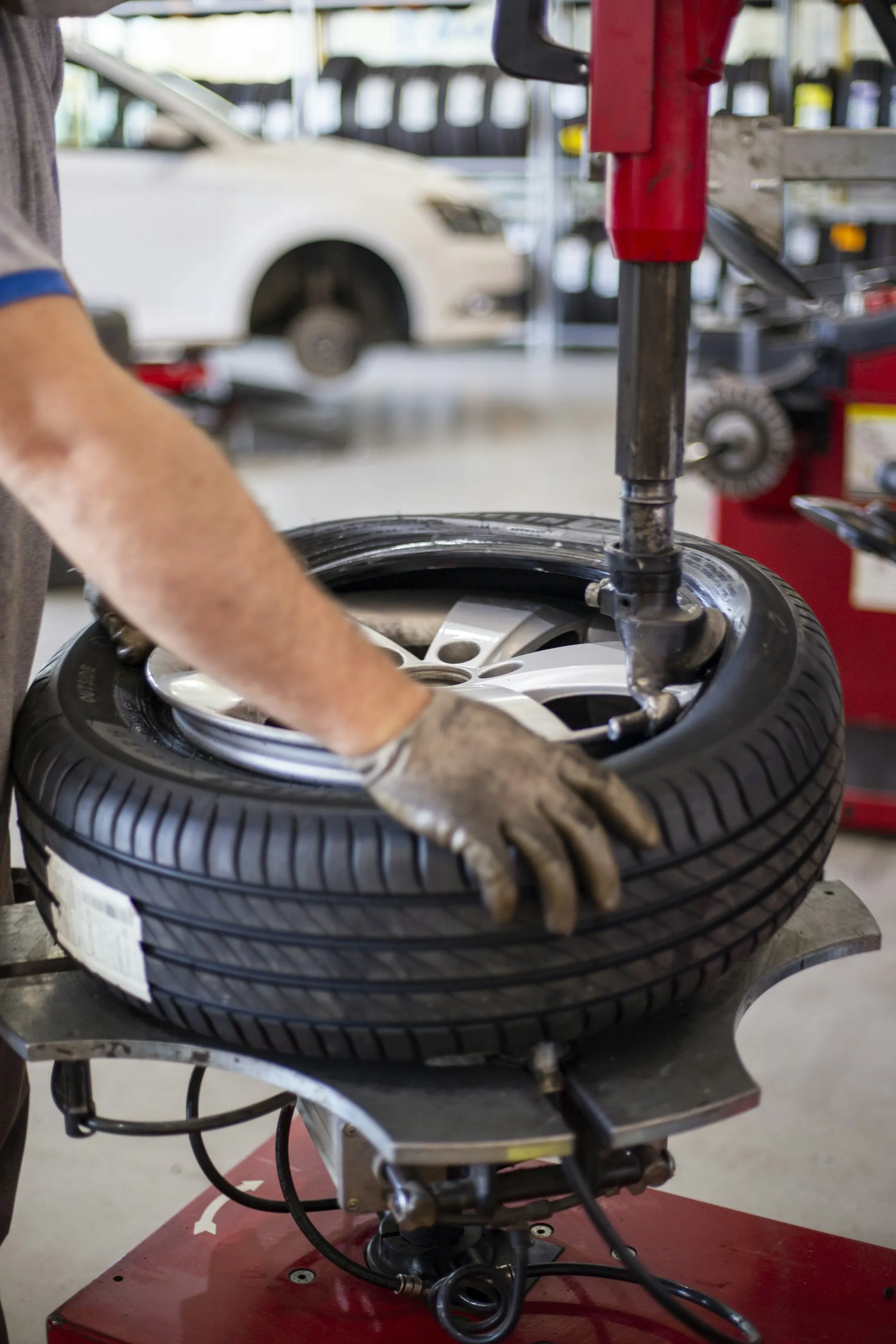 Gloved hand cleaning a car wheel with a brush